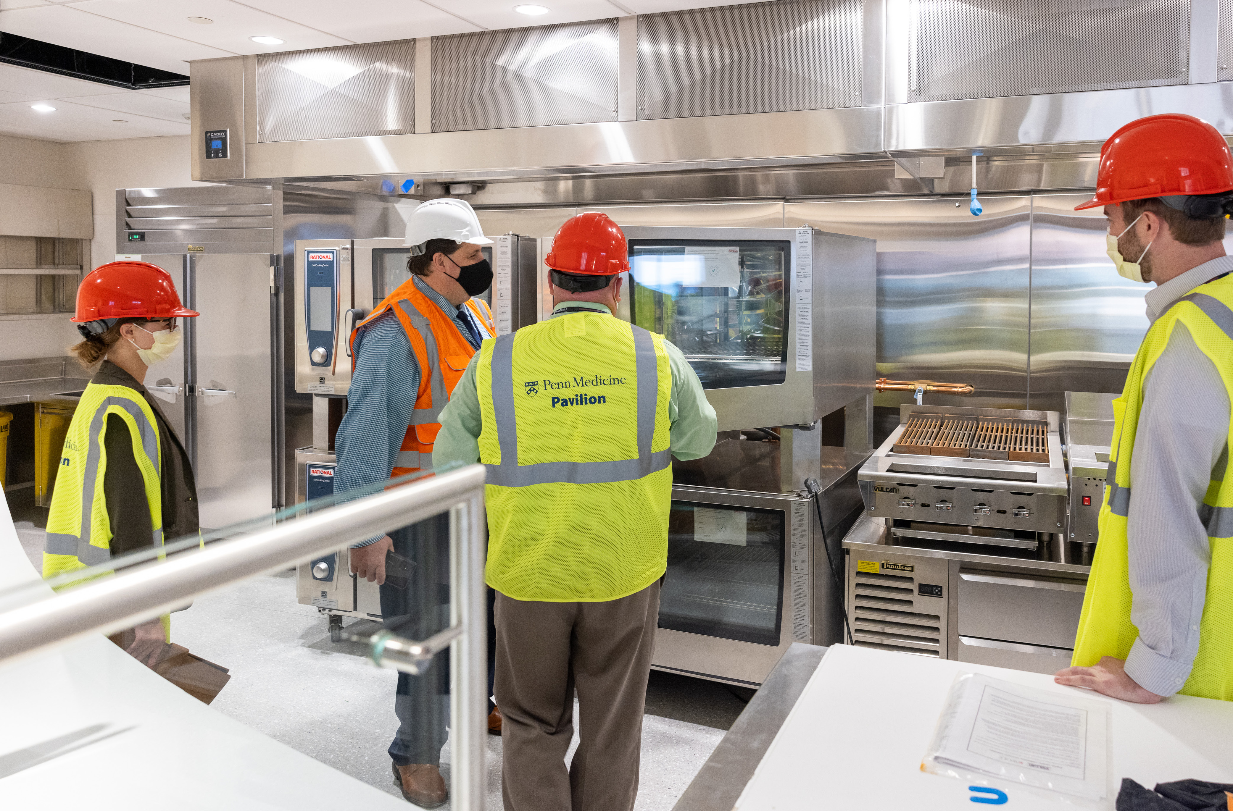 HUP Resident District Manager of Food and Nutrition Anthony Avalone, wearing the orange vest, and members of the Food Services management team inspect new equipment in the Pavilion servery prior to opening.